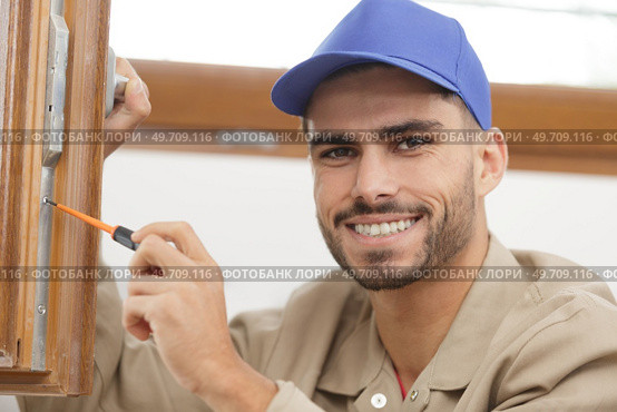 young man contractor screwing window handle mechanism. Стоковое фото, агентство Ingram Publishing / Фотобанк Лори