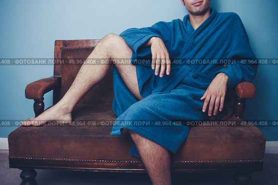 Young man in bathrobe sitting on a sofa. Стоковое фото, агентство Ingram Publishing / Фотобанк Лори