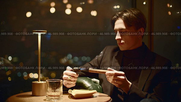 Young man lights cigar with lighter in institution. Стоковое фото, фотограф David Kashakhi / Фотобанк Лори