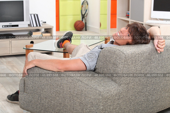 Young man relaxing on sofa. Стоковое фото, агентство Ingram Publishing / Фотобанк Лори