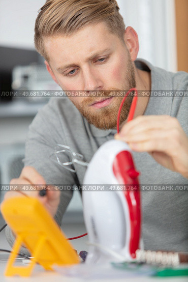 young man repairing iron inhis workspace. Стоковое фото, агентство Ingram Publishing / Фотобанк Лори