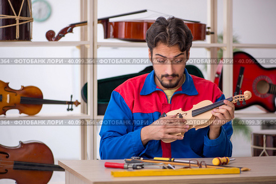 Young man repairing musical instruments at workshop. Стоковое фото, фотограф Elnur / Фотобанк Лори