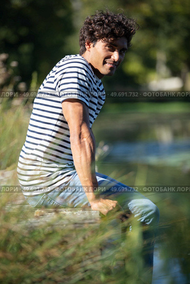 young man sitting on a pontoon by a lake. Стоковое фото, агентство Ingram Publishing / Фотобанк Лори