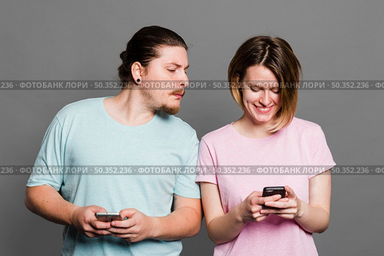 young man spying peeking smartphone her girlfriend using mobile phone. Стоковое фото, агентство Ingram Publishing / Фотобанк Лори