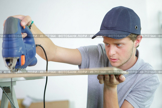 Young man using electric jigsaw. Стоковое фото, агентство Ingram Publishing / Фотобанк Лори