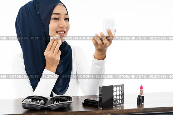 Young Muslim woman hold cosmetic and looking to camera to review product as vlog and blogger on white background taken in studio. Using for Fashion and beauty concept. Стоковое фото, агентство Ingram Publishing / Фотобанк Лори