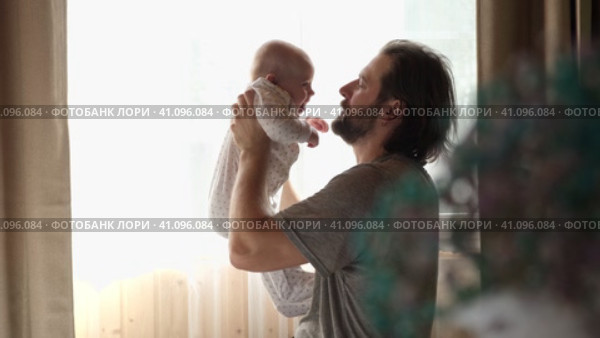 Young neo father is playing with his newborn baby in a nursery morning. Father's Day. Father holds in hands little Child and Plays with him. Concept of children, baby, parenthood, childhood, family. Стоковое видео, видеограф Марина Демидюк / Фотобанк Лори