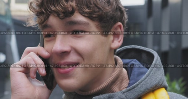 Young person messaging on smartphone, grinning while listening amid rainy urban backdrop, radiating joyful digital connectivity. Стоковое видео, видеограф Данил Руденко / Фотобанк Лори