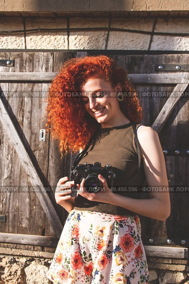 Young redhead photographer woman enjoying her passion outdoors. Стоковое фото, агентство Ingram Publishing / Фотобанк Лори