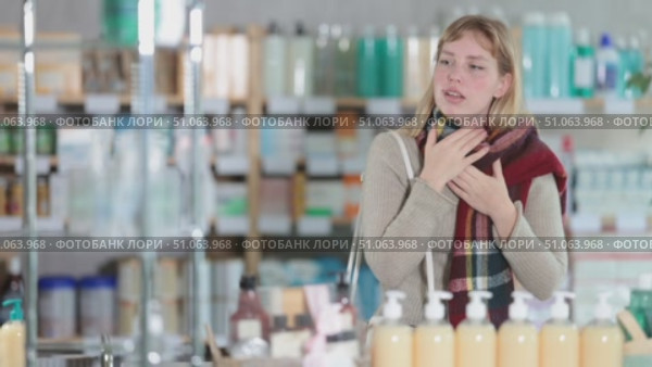 Young woman buyer with sore throat choosing medicines and hygiene products in pharmacy. Стоковое видео, видеограф Яков Филимонов / Фотобанк Лори