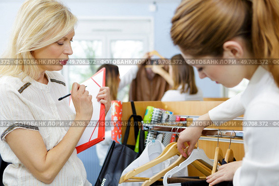 young woman choosing clothes on a rack in a showroom. Стоковое фото, агентство Ingram Publishing / Фотобанк Лори
