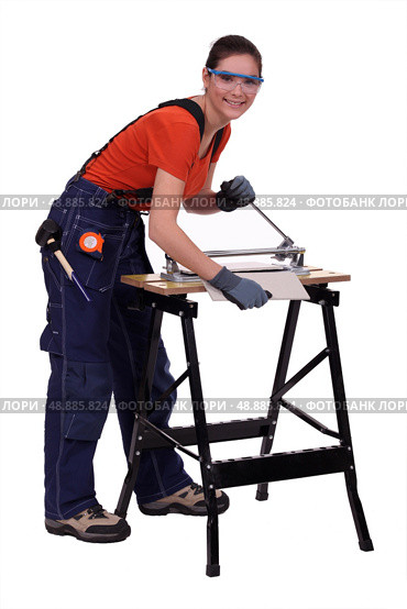 Young woman cutting a tile. Стоковое фото, агентство Ingram Publishing / Фотобанк Лори