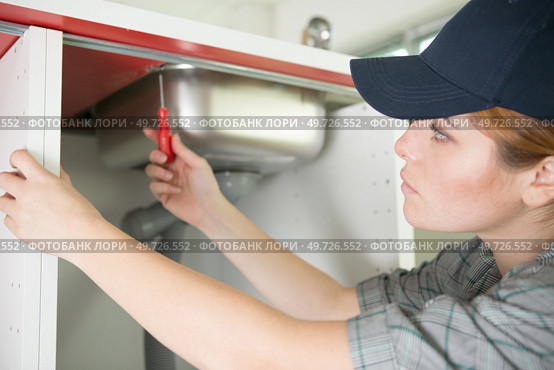 young woman fixes the plumbing under the kitchen sink. Стоковое фото, агентство Ingram Publishing / Фотобанк Лори