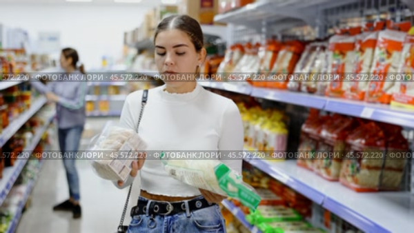 Young woman in supermarket buys daily groceries, pasta Chinese noodles. Стоковое видео, видеограф Яков Филимонов / Фотобанк Лори