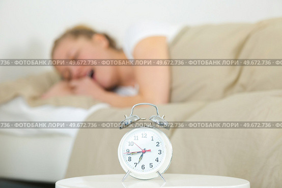 young woman on white bed yawn awakening with alarm clock. Стоковое фото, агентство Ingram Publishing / Фотобанк Лори