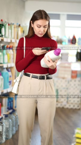 Young woman scanning barcode on mobile large bottle with detergent in household store. Стоковое видео, видеограф Яков Филимонов / Фотобанк Лори