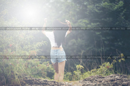 Young woman with windy messy hair backlit by sun selective focus toned image, sun flares. Стоковое фото, агентство Ingram Publishing / Фотобанк Лори