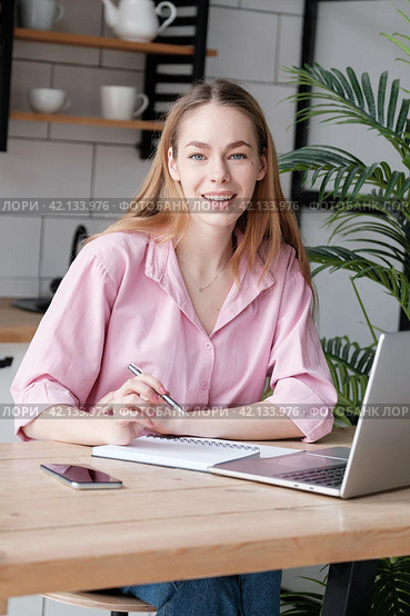 Young woman writing, taking notes, female student smiling sitting with laptop. Стоковое фото, фотограф Оксана Гильман / Фотобанк Лори