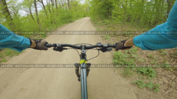 Захватывающее экстремальное видео поездки на горном велосипеде. Велосипедист в синей рубашке с длинными рукавами и перчатках едет по грунтовой дороге в лесу. Вид от первого лица. Стоковое видео, видеограф Воловодов Владимир / Фотобанк Лори