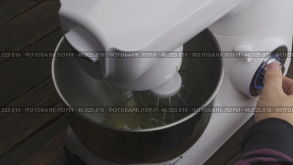 Замедленная съемка. Шеф-повар опускает венчик в чашу планетарного миксера и включает его. Взбивает сливки. Вид сверху. Кухонные принадлежности. Стоковое видео, видеограф Александр Собко / Фотобанк Лори