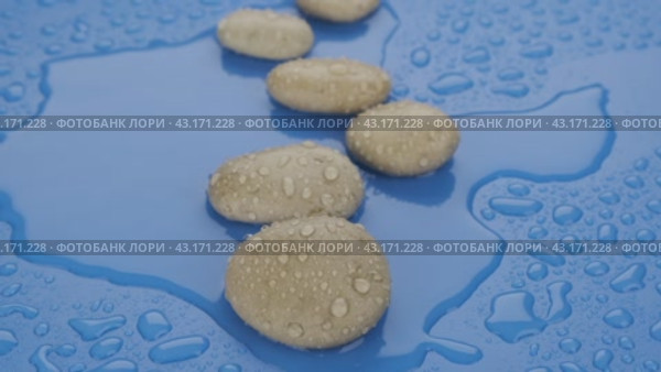 Замедленная съемка. Зигзаг из белых камней и капля воды, падающая на синем фоне. Крупный план. Slow motion. Zigzag of white stones and a drop of water falling on a blue background. Стоковое видео, видеограф Александр Собко / Фотобанк Лори