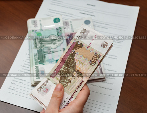 Заработанные деньги в женских руках на фоне трудового договора. Стоковое фото, фотограф Игорь Низов / Фотобанк Лори