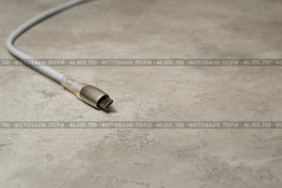 Зарядный кабель micro USB на сером фоне. Зарядный шнур для бытовых электрических приборов. Редакционное фото, фотограф Sergei Gorin / Фотобанк Лори