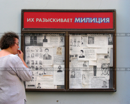 Женщина читает информацию на  доске "Их разыскивает милиция" (2008 год). Редакционное фото, фотограф lana1501 / Фотобанк Лори