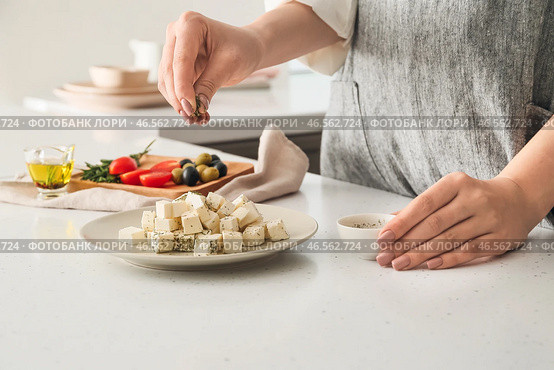 Женщина добавляет специи к вкусному сыру фета на столе. Стоковое фото, фотограф Pixel_shot / Фотобанк Лори