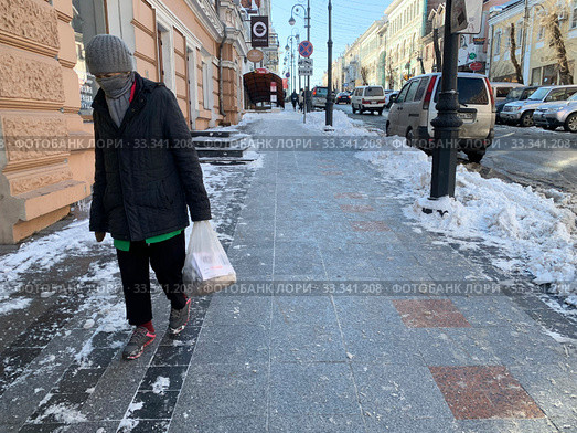 Женщина с замотанным шарфом лицом идет по улице Светланская в начале марта (2020 год). Редакционное фото, фотограф Овчинникова Ирина / Фотобанк Лори