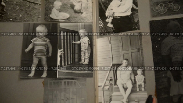 Женщина смотрит старый фотоальбом с детскими фотографиями, период 1970-1980 СССР (2015 год). Редакционное видео, видеограф Mikhail Erguine / Фотобанк Лори
