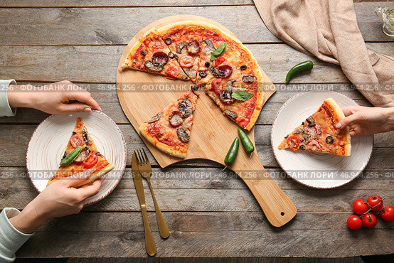 Женщины едят вкусную пиццу за столом. Стоковое фото, фотограф Pixel_shot / Фотобанк Лори