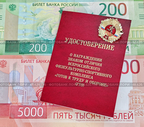 Золотой знак отличия всероссийского физкультурно-спортивного комплекса "Готов к труду и обороне (ГТО)" VI ступени и удостоверение Министерства спорта Российской Федерации и российские деньги. Редакционное фото, фотограф Цибаев Алексей / Фотобанк Лори